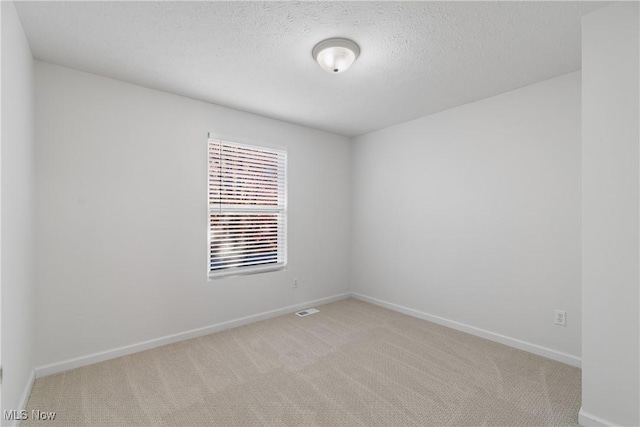 spare room with light colored carpet and a textured ceiling