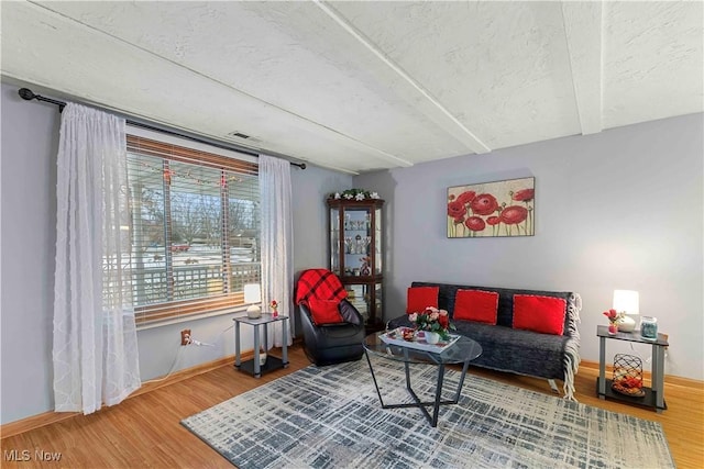 sitting room featuring hardwood / wood-style floors, a textured ceiling, and beamed ceiling