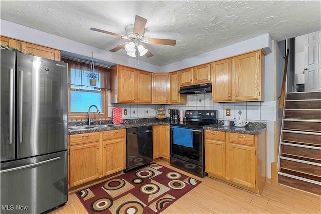 kitchen featuring sink, black appliances, light hardwood / wood-style floors, a textured ceiling, and decorative backsplash