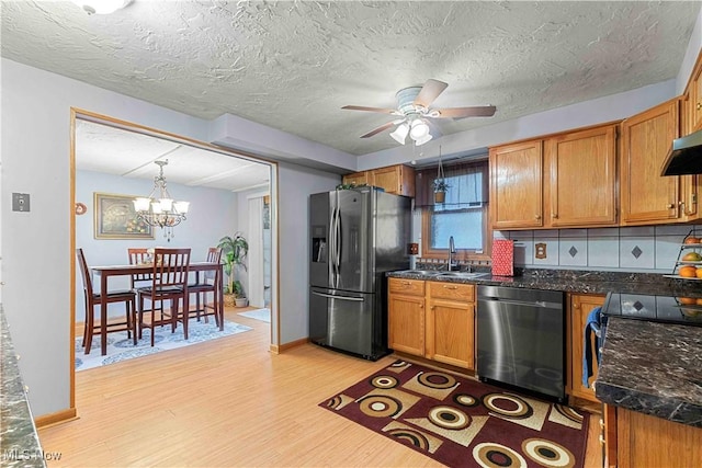 kitchen with ceiling fan with notable chandelier, stainless steel appliances, light hardwood / wood-style floors, decorative backsplash, and decorative light fixtures