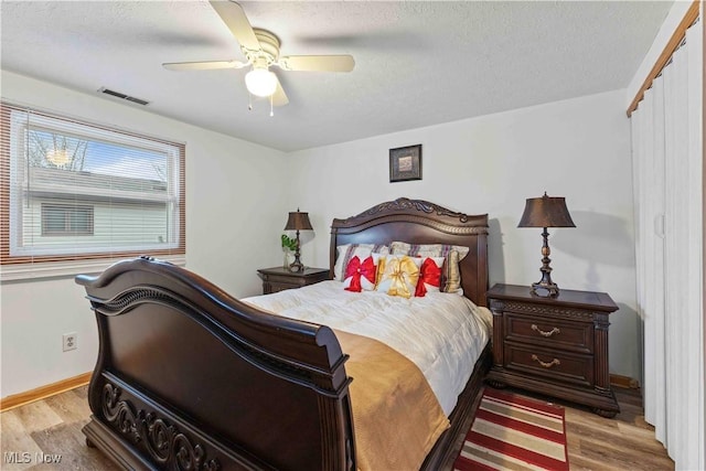 bedroom featuring ceiling fan, light hardwood / wood-style flooring, and a textured ceiling