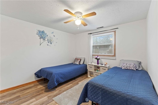 bedroom featuring ceiling fan, a textured ceiling, and light hardwood / wood-style floors