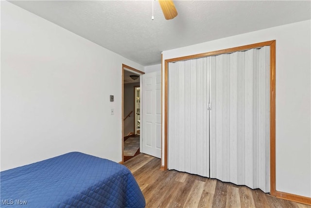 bedroom featuring ceiling fan, hardwood / wood-style floors, a textured ceiling, and a closet