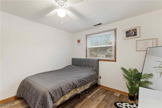 bedroom featuring hardwood / wood-style floors, a textured ceiling, and ceiling fan