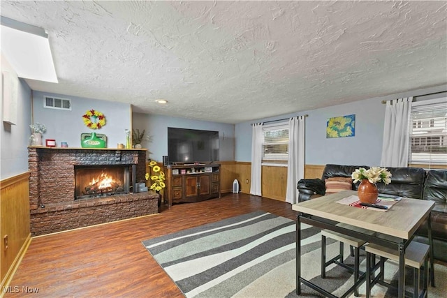 living room featuring wood-type flooring, a wealth of natural light, a textured ceiling, and a fireplace