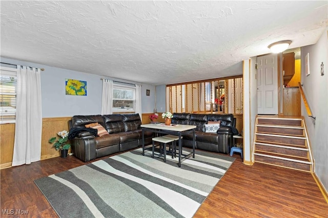 living room featuring dark hardwood / wood-style floors, a textured ceiling, and wood walls