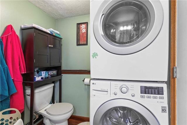 clothes washing area featuring stacked washer and clothes dryer and a textured ceiling