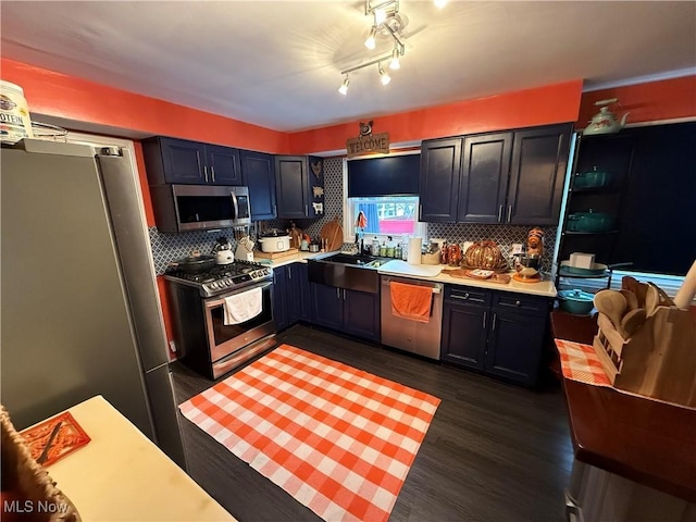 kitchen featuring dark wood-type flooring, appliances with stainless steel finishes, sink, and tasteful backsplash