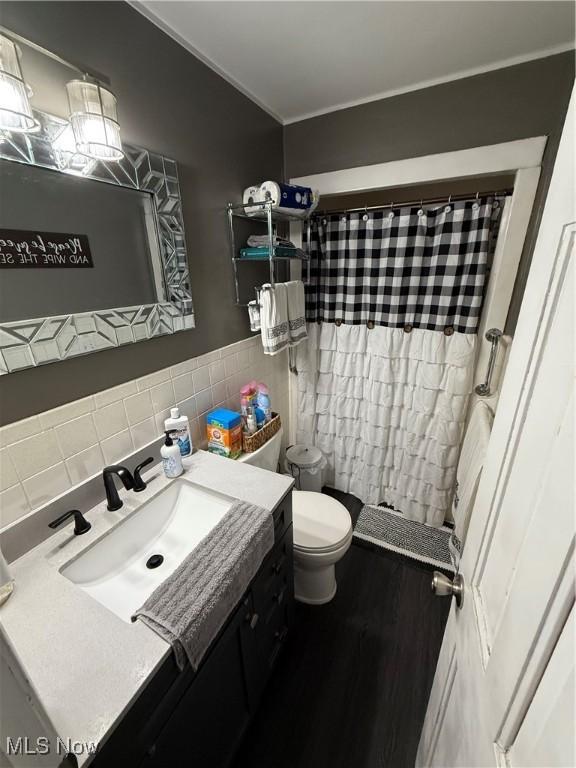 bathroom featuring vanity, toilet, curtained shower, and tile walls