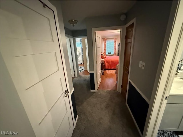 corridor with washer / clothes dryer and dark carpet