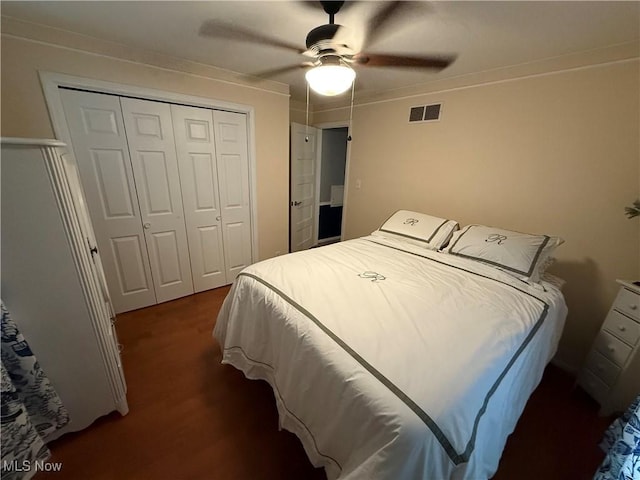 bedroom with dark wood-type flooring, ceiling fan, and a closet