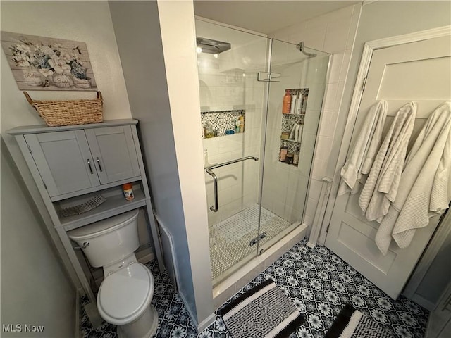 bathroom featuring tile patterned floors, a shower with door, and toilet