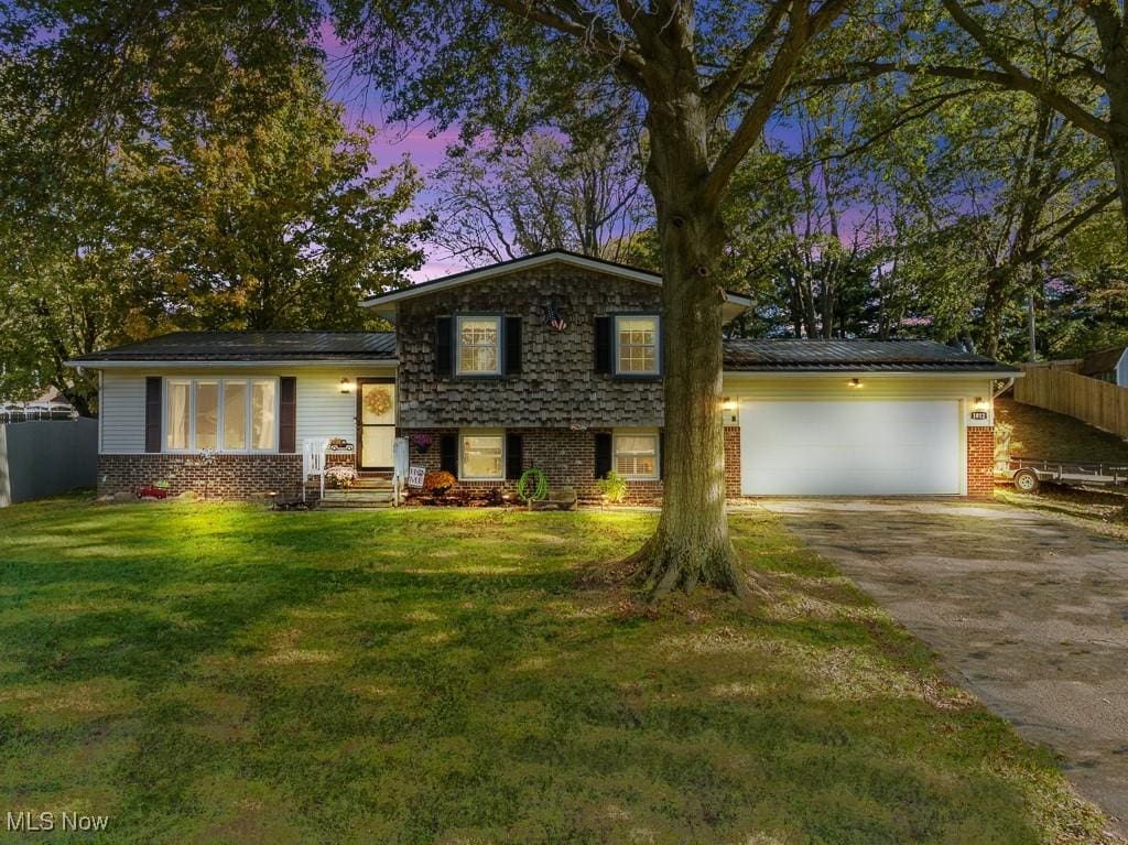 tri-level home featuring a garage and a yard