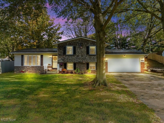 tri-level home featuring a garage and a yard