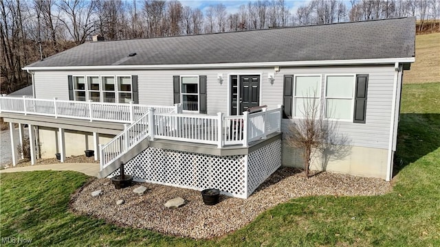 rear view of house featuring a wooden deck and a yard