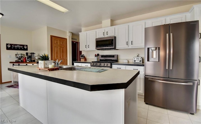 kitchen featuring light tile patterned flooring, sink, white cabinets, a kitchen island with sink, and stainless steel appliances