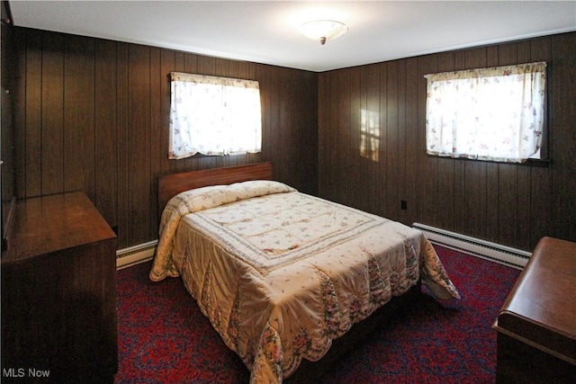 bedroom featuring multiple windows, a baseboard radiator, and wood walls