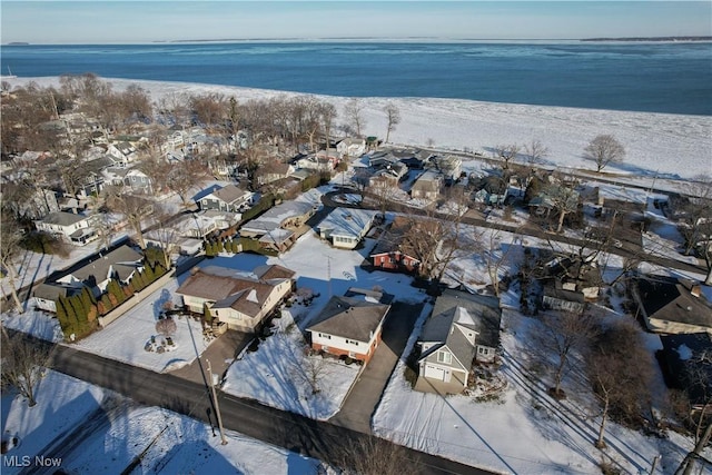 snowy aerial view with a water view and a beach view