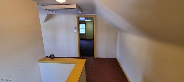 hallway with lofted ceiling and dark carpet