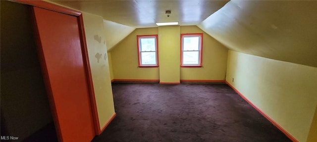 additional living space featuring lofted ceiling and dark carpet