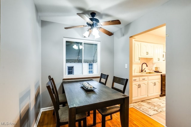 dining area with ceiling fan, sink, wine cooler, and light wood-type flooring