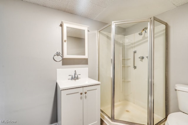 bathroom featuring a shower with door, vanity, a drop ceiling, and toilet