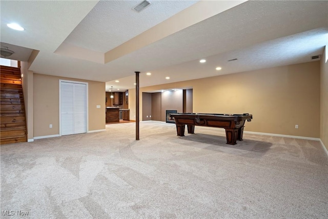 game room with pool table, a raised ceiling, light carpet, and a textured ceiling