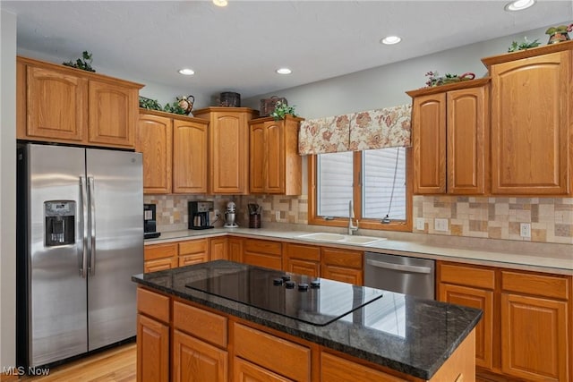 kitchen featuring a kitchen island, appliances with stainless steel finishes, sink, dark stone counters, and decorative backsplash