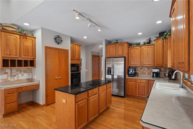 kitchen featuring sink, a center island, light hardwood / wood-style flooring, decorative backsplash, and black appliances