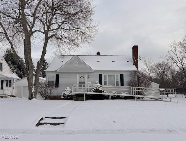 snow covered rear of property featuring an outbuilding and a garage