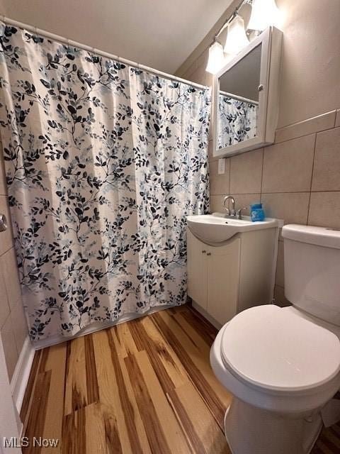 bathroom featuring wood-type flooring, toilet, tile walls, and vanity