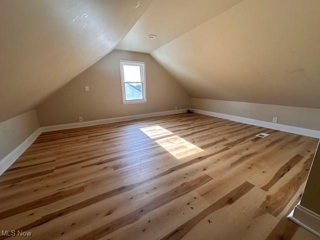 additional living space with vaulted ceiling and light wood-type flooring