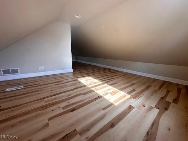 additional living space featuring vaulted ceiling and light wood-type flooring