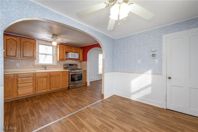 kitchen with sink, crown molding, light hardwood / wood-style floors, and gas stove