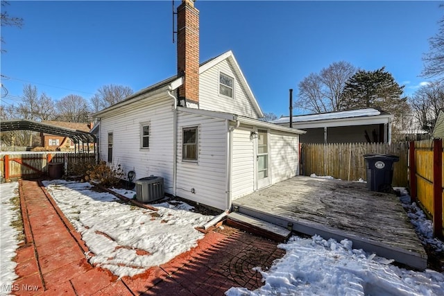 snow covered house with cooling unit and a deck