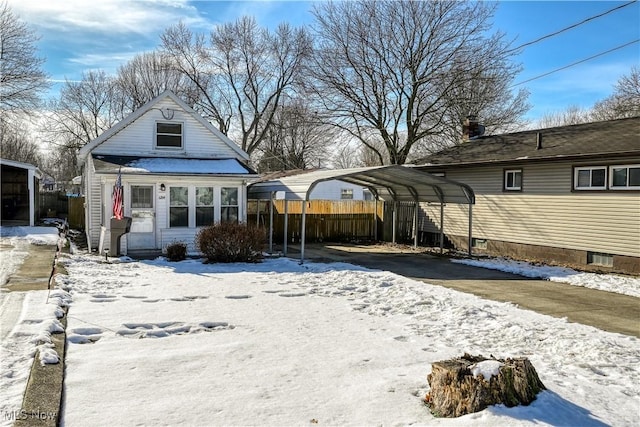 snow covered rear of property with a carport