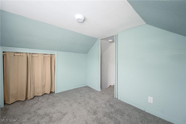 bonus room with light carpet, vaulted ceiling, and a textured ceiling