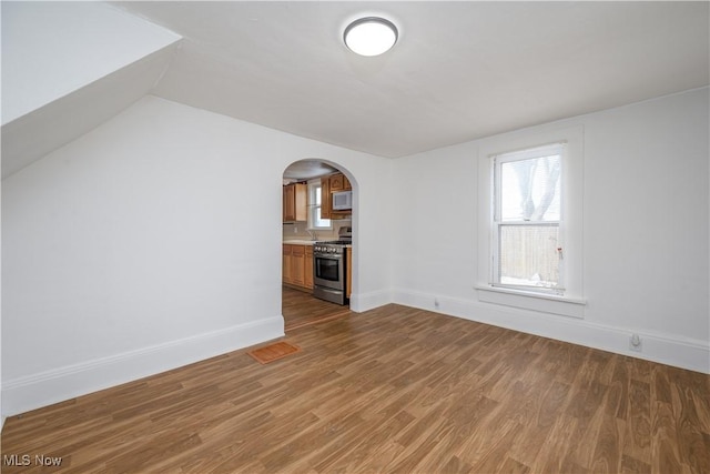 unfurnished living room with wood-type flooring and vaulted ceiling