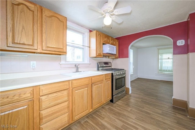 kitchen featuring ceiling fan, sink, stainless steel gas range, and dark hardwood / wood-style flooring