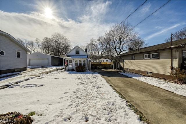 yard covered in snow featuring a garage, an outdoor structure, and a carport