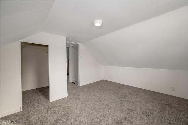 bonus room with vaulted ceiling and carpet floors