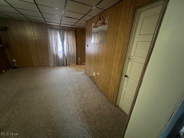 basement with a paneled ceiling and wood walls