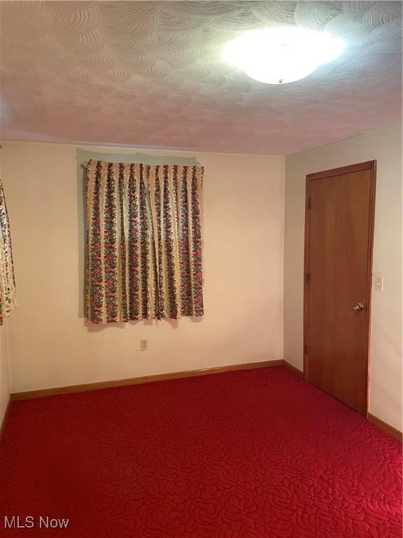 empty room featuring a textured ceiling and carpet