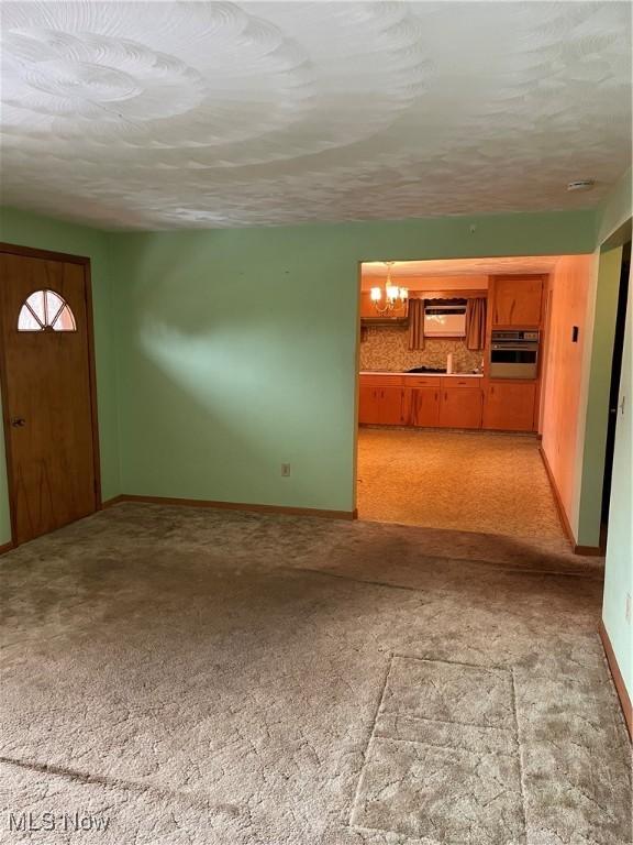 unfurnished living room with light colored carpet and a textured ceiling