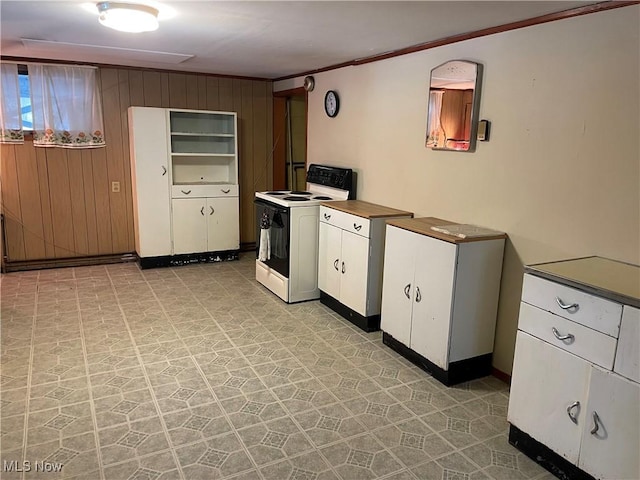 kitchen with crown molding, wooden walls, white electric range oven, and white cabinets