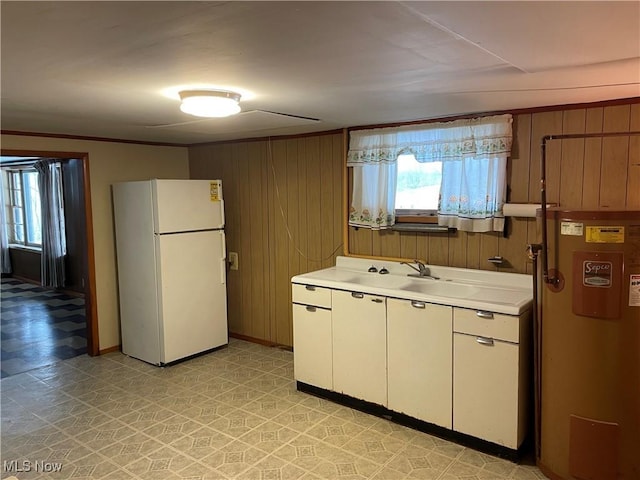 kitchen featuring plenty of natural light, wooden walls, sink, and white fridge