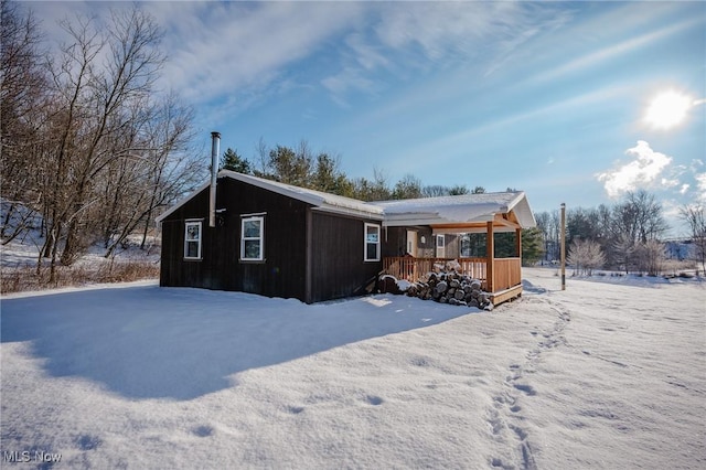 snow covered back of property with a porch