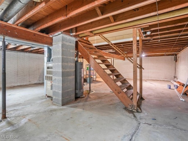 basement featuring water heater and brick wall