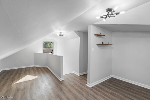 additional living space with wood-type flooring, vaulted ceiling, and an inviting chandelier