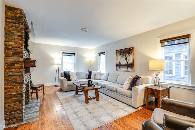 living room featuring a stone fireplace and light wood-type flooring